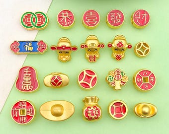 May include: Assortment of gold-colored charms with red and green enamel accents. The charms feature Chinese characters and symbols, including a lucky cat, a money bag, and a coin with the character for "fortune".