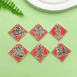 Puede incluir: Seis amuletos rojos en forma de diamante con ribetes dorados y caracteres chinos negros. Los caracteres son "福", "恭喜发财", "平安", "健康", "幸运", y "招财".