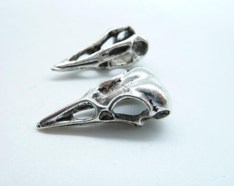 May include: Two silver bird skull charms with intricate details. The charms are small and delicate, perfect for adding a touch of whimsy to jewelry or crafts.