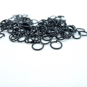 Może przedstawiać: Duża sterta czarnych metalowych kółek do łączenia. Wszystkie kółka są tej samej wielkości i ułożone w przypadkowy sposób.