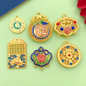May include: Six gold-colored pendants with intricate designs and colorful enamel. The pendants feature Chinese characters, abacus beads, and floral patterns.
