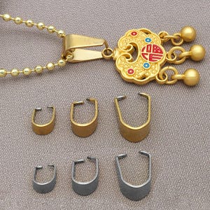 May include: Gold-coloured pendant necklace with a decorative charm and matching gold-coloured clasps. The charm features red and blue accents. Below are three gold and three silver-coloured clasps of varying sizes.