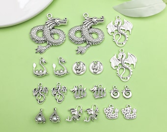 May include: A collection of silver-toned metal dragon charms, including a variety of dragon designs, some with wings, some with scales, and some with a more stylized look. There are also some round charms with dragon designs and some charms with a pearl-like bead.