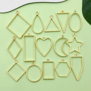 Puede incluir: Un conjunto de 15 bandejas colgantes de metal de color dorado en varias formas, incluyendo un círculo, un cuadrado, un rectángulo, un corazón, una estrella, una luna creciente y un triángulo. Las bandejas están diseñadas para el moldeo de resina y la elaboración de joyas.