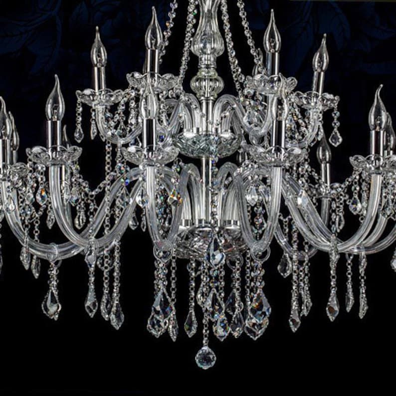 May include: A large, crystal chandelier with multiple arms and hanging crystals. The chandelier is made of clear glass and has a silver finish.