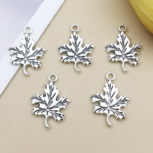 May include: Five silver maple leaf charms with a detailed design. The charms are perfect for jewelry making, scrapbooking, and other craft projects.