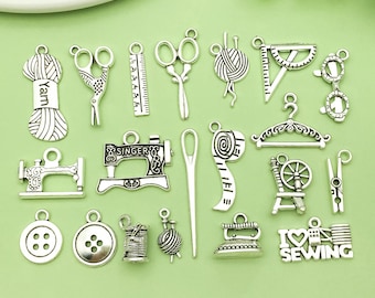 Puede incluir: Colección de dijes de costura plateados, que incluyen tijeras, máquinas de coser, hilo, cinta métrica y botones. Los dijes están dispuestos sobre una superficie verde claro, perfectos para proyectos de manualidades.