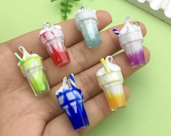 May include: Six colourful miniature plastic milkshake charms with white whipped cream and a straw. Each charm has a different colour swirl pattern.
