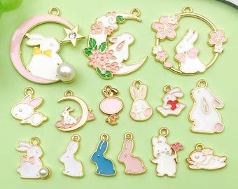 May include: A collection of gold-toned metal charms featuring white rabbits with pink and blue accents. Some charms include moons, flowers, and pearls. These decorative charms are ideal for jewelry making or crafting projects.