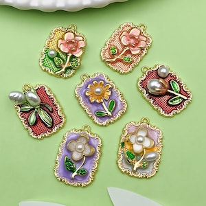 May include: Seven gold-toned metal charms with enamel flower designs. Each charm features a different flower with a pearl accent. The charms are rectangular with a decorative border.