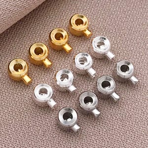 May include: Assortment of silver and gold metal end caps with a loop for attaching to a cord or chain. The end caps have a rounded, cup-like shape.