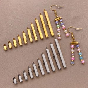 Puede incluir: Dos pares de pendientes con componentes metálicos dorados y plateados. Un par presenta una cascada de cuentas de colores. El otro par tiene un diseño similar. Los pendientes se muestran sobre un fondo neutro.