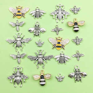 Puede incluir: Una colección de abalorios de abeja de plata y oro con detalles de esmalte negro y amarillo. Los abalorios son perfectos para la elaboración de joyas, el scrapbooking y otros proyectos de manualidades.
