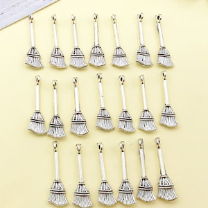 May include: Twenty silver-toned metal charms shaped like brooms. Each charm has a loop at the top for attaching to a necklace, bracelet, or other jewellery.