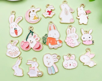 May include: A collection of colorful bunny charms with gold-tone metal accents. The charms feature various designs, including bunnies with carrots, cherries, and hearts. The charms are white, pink, orange, and blue.