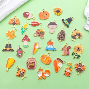 May include: Assortment of enamel charms featuring autumnal themes, including pumpkins, acorns, turkeys, mushrooms, squirrels, and a jar labeled "JAM".