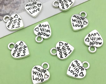 May include: Ten silver heart-shaped charms with the text "Made with Love" on each charm. The charms have a small loop at the top for attaching to jewelry or other crafts.