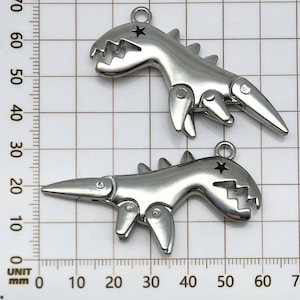 May include: Two silver-toned dinosaur charms with articulated legs and a star on the head. The charms are approximately 4 cm long.