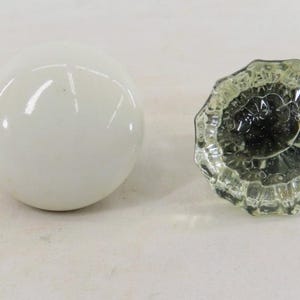 Könnte beinhalten: Eine weiße Keramik-Tasse mit schwarzem Henkel und dem Text "But First, Coffee" in schwarzer, fetter Schrift. Die Tasse steht auf einer weißen Oberfläche.