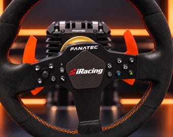 Puede incluir: Un volante de carreras negro con costuras naranjas y levas de cambio naranjas. El centro presenta el logotipo de Fanatec y un emblema de iRacing. El volante incluye varios botones negros con iconos blancos, flechas de dirección y letras.