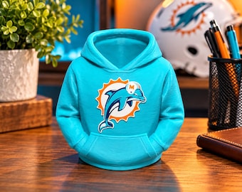 Könnte beinhalten: Eine helltürkisfarbene Miniatur-Kapuzenpullover-Figur mit einer zentralen Grafik eines Delfins, der einen Helm trägt, innerhalb eines orangefarbenen Sonnenemblems. Der Kapuzenpullover verfügt über eine Kapuze, lange Ärmel und eine Kängurutasche.