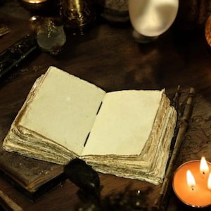 May include: An open, aged book with thick, yellowed pages sits on a dark wooden surface. The book's pages are blank, suggesting a journal or spellbook. Lit candles and other mystical items surround the book, creating a mysterious atmosphere.