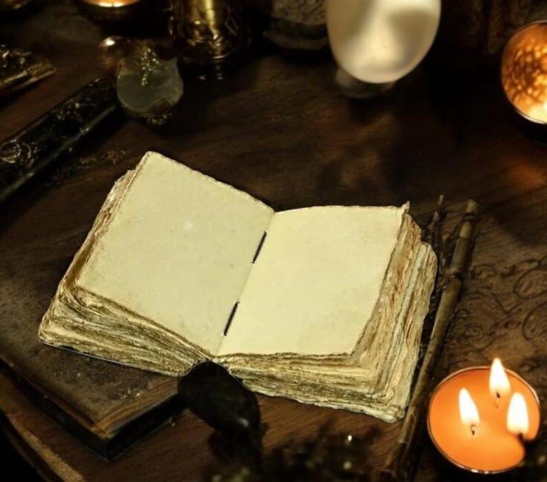 May include: An open, aged book with thick, yellowed pages sits on a dark wooden surface. The book's pages are blank, suggesting a journal or spellbook. Lit candles and other mystical items surround the book, creating a mysterious atmosphere.