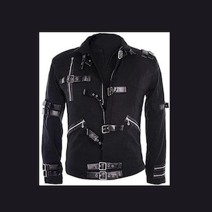 May include: A black jacket featuring multiple silver-toned metal buckles and straps across the front and sleeves. The garment includes a central zipper closure, diagonal zippered pockets, and adjustable buckle straps on the cuffs and shoulders.