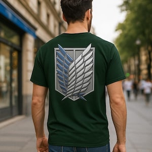 Puede incluir: Camiseta verde oscuro con un emblema estilizado de alas azules y blancas en la espalda. El emblema está dentro de una forma de escudo gris. La persona lleva vaqueros azules.