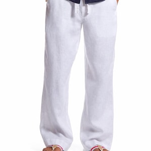 May include: White linen trousers with a drawstring waist. The trousers are worn with navy blue flip-flops with red and gold details. The model is wearing a navy blue shirt.
