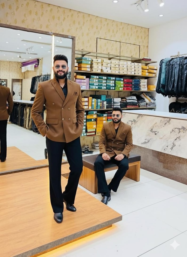 Pode incluir: Um blazer marrom de abotoamento duplo e cal&ccedil;as pretas. O blazer tem um design cl&aacute;ssico. A imagem mostra uma loja de roupas, com um espelho e prateleiras de roupas ao fundo.