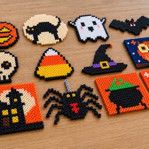 Könnte beinhalten: Eine Sammlung von zwölf Halloween-Motiven aus Bügelperlen, darunter ein Kürbis, eine schwarze Katze, ein Geist, eine Fledermaus, ein Totenkopf, ein Zuckermais, ein Hexenhut, eine Eule, ein Spukhaus, eine Spinne, ein Kessel und ein Grabstein mit der Aufschrift RIP.