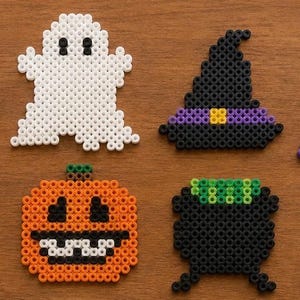 May include: A set of eight Halloween-themed fuse bead designs including a white eyeball with a green iris, a white ghost, a black witch hat, a purple and green witch face, yellow and orange candy corn, an orange pumpkin, a black cauldron, and a gray tombstone.