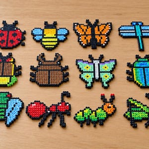 May include: A collection of twelve insect and butterfly figures crafted from small, colorful plastic beads. The set includes a red ladybug, a yellow and black bee, a monarch butterfly, a blue dragonfly, a beetle, a green butterfly, and an ant.