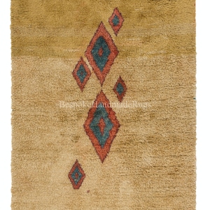 May include: Mustard-coloured, shaggy rug featuring a geometric diamond pattern. The diamonds are in shades of red and teal, contrasting against the rug's neutral background. The rug has a soft, textured appearance, suggesting a comfortable and inviting feel.