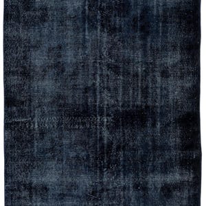 May include: A rectangular, dark blue rug with a distressed, vintage appearance. The rug has a faded, mottled effect with vertical striations, creating a textured look. The color is a deep navy with lighter blue highlights.