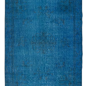 May include: A rectangular, distressed-look rug in shades of blue. The rug features a central field of solid blue with darker blue and gray accents. The border is a darker shade of blue with a subtle pattern. The rug has a vintage, worn appearance.