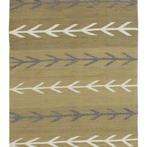 Puede incluir: Una alfombra rectangular tejida con un fondo beige y filas de diseños de flechas en blanco y gris. La alfombra tiene un borde negro en la parte inferior y un borde a rayas en la parte superior.