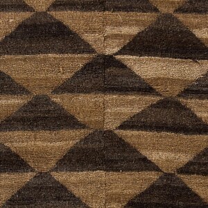 May include: Close-up of a textured fabric with a repeating geometric pattern. The design features alternating rows of brown and dark brown triangles, creating a bold, graphic effect. The fabric appears to be woven or tufted.