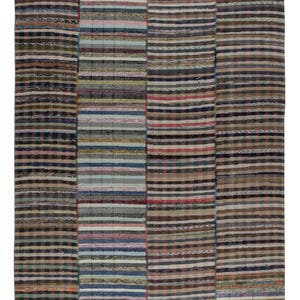 May include: A rectangular rug with a patchwork design. The rug features vertical stripes in various colors, including blue, brown, pink, and green. The stripes are of varying widths, creating a textured appearance. The rug is likely made of woven fabric.
