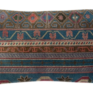 Puede incluir: Cojín decorativo rectangular con un diseño detallado y estampado. El cojín presenta un fondo turquesa con bandas marrones, grises y rojas. Motivos geométricos y florales en varios colores adornan la superficie, creando una estética vintage.