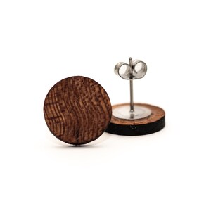 May include: A pair of round wooden earrings with a natural wood grain pattern. The earrings have silver posts and backs.