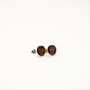 May include: A pair of round wooden earrings with a dark brown outer ring and a lighter brown center. The earrings have silver posts.