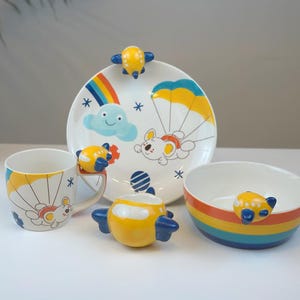 May include: A white ceramic mug with a black handle and the text "But First, Coffee" in a black, handwritten-style font. The mug is on a white surface.