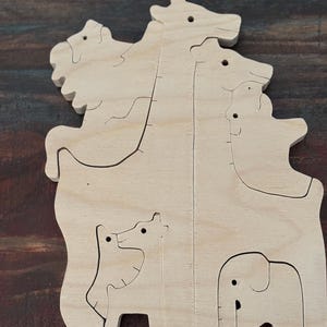 May include: Wooden animal puzzle featuring a giraffe, elephant, and other animals. The puzzle is made of light-colored wood and has a simple, clean design. The pieces are cut to fit together, creating a fun and educational toy.