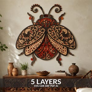 May include: A multi-layered wooden wall art piece shaped like a beetle, featuring intricate laser-cut floral patterns in black, natural wood, and orange tones. The design consists of 5 layers, with text at the bottom reading 5 LAYERS SVG CDR DXF PDF AI.