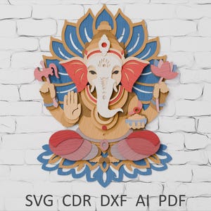 Puede incluir: Una pieza de arte mural de madera en capas que representa a la deidad hindú Ganesha. La obra de arte presenta un cuerpo marrón claro, detalles en rojo y rosa y detalles de flor de loto azul. El texto "SVG CDR DXF AI PDF" está en la parte inferior.