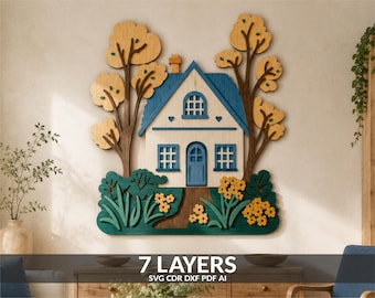 May include: A multi-layered wooden wall art piece featuring a house with a blue roof, a central door, and windows. The scene includes two tall trees with yellow foliage on either side and green bushes with yellow flowers at the base. Text reads 7 LAYERS SVG CDR DXF PDF AI.