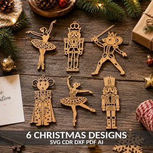 May include: Six laser-cut wooden Christmas ornaments featuring two ballerinas, two nutcrackers, and two mouse characters. The ornaments are arranged on a wooden surface alongside a card with the text Magic of Creation and 6 CHRISTMAS DESIGNS.