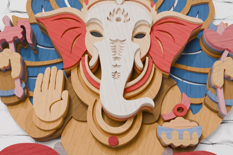 May include: A multi-layered wooden wall art piece depicting the deity Ganesha. The design features a white face and trunk, red ears, and blue accents. Ganesha is shown with an open palm gesture, holding a pink lotus flower and a small bowl.